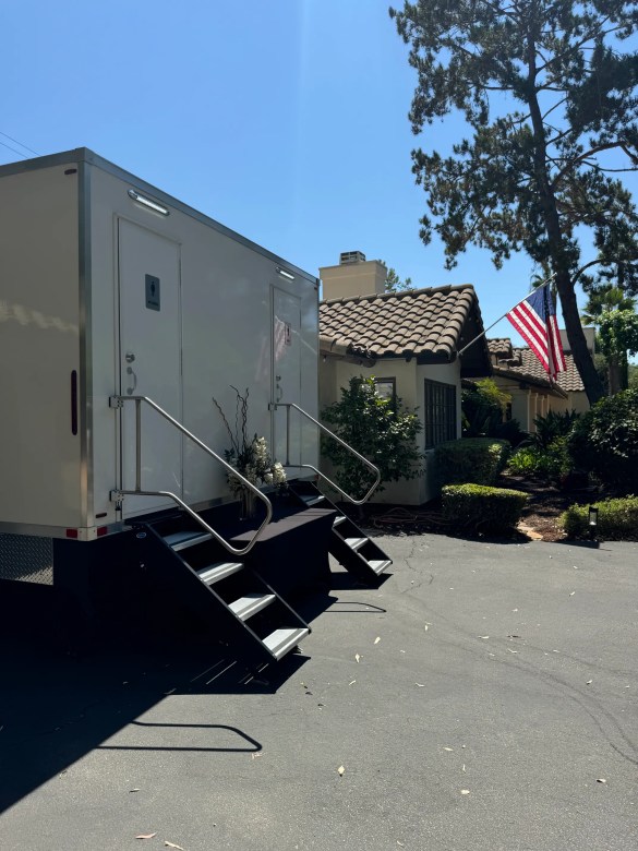 VIP Rentals, LLC luxury restroom trailer parked at a backyard event in Southern California with an American flag in the background